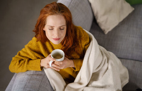 Young,Woman,Relaxing,On,A,Sofa,With,Ca,Mug,Of