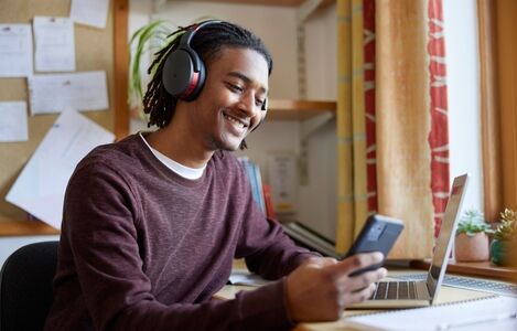 Male,University,Or,College,Student,Wearing,Wireless,Headphones,With,Laptop